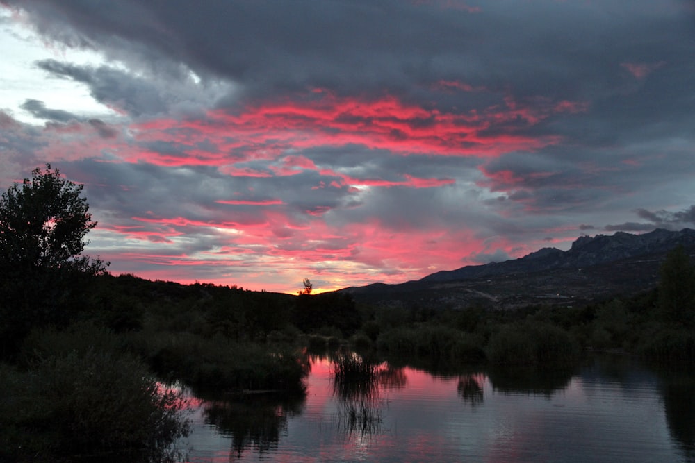 a body of water with trees and mountains in the background