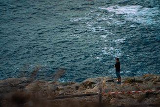 a man standing on a rocky shore