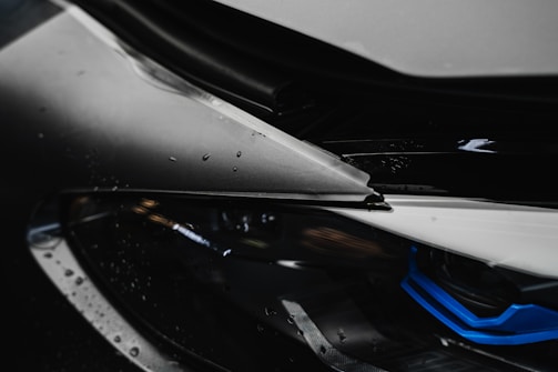 Close-up of a luxury car’s headlight with rain droplets on the surface.