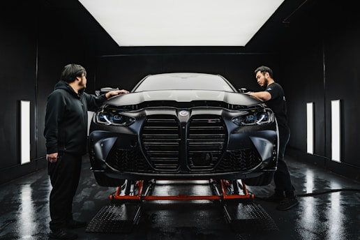 a couple of men standing next to a car in a garage