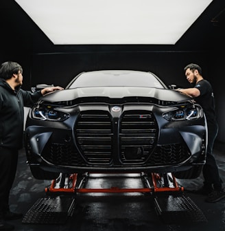 a couple of men standing next to a car in a garage