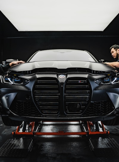 a couple of men standing next to a car in a garage