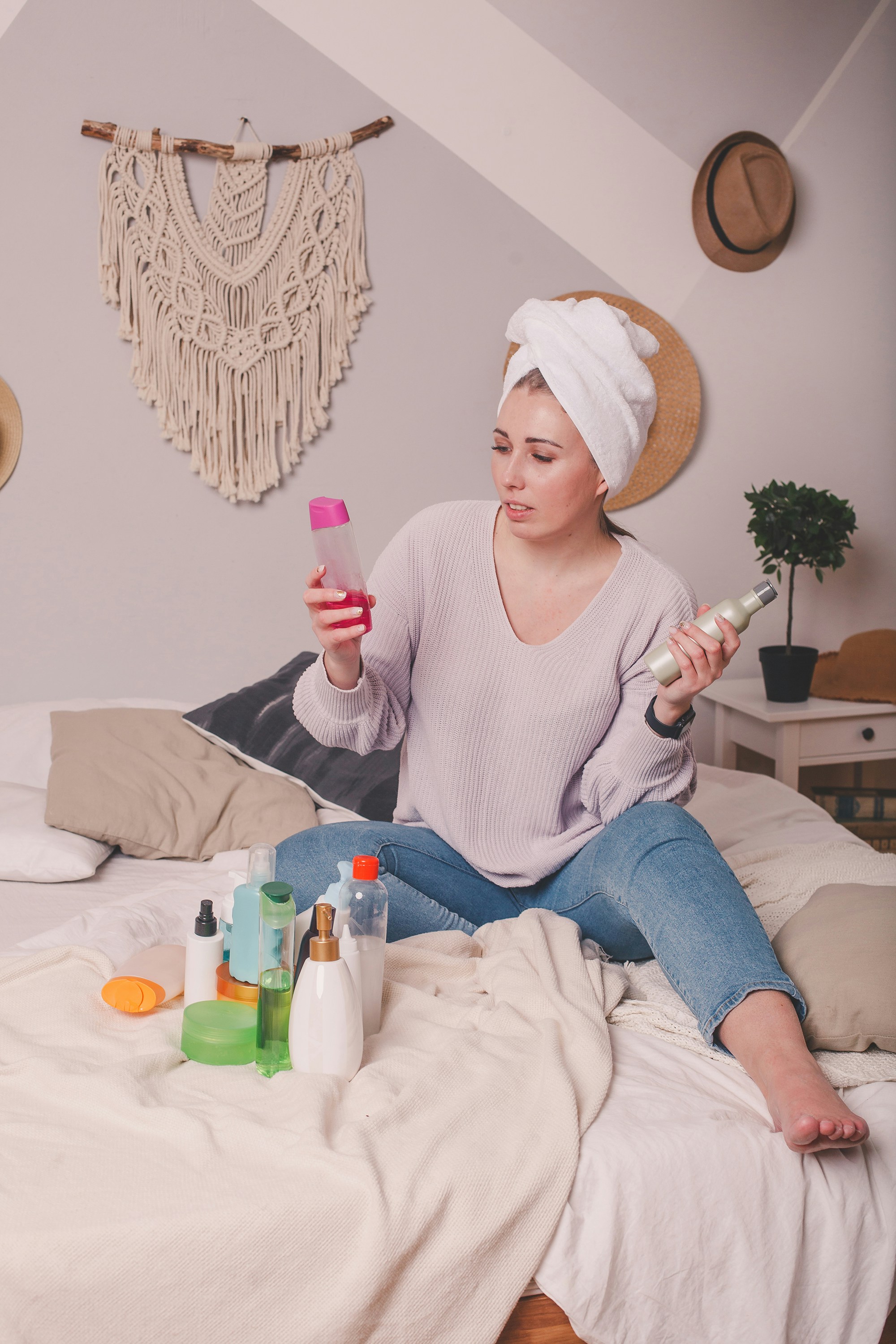 Woman with towel wrapped around head doing night skincare routine with soft lighting