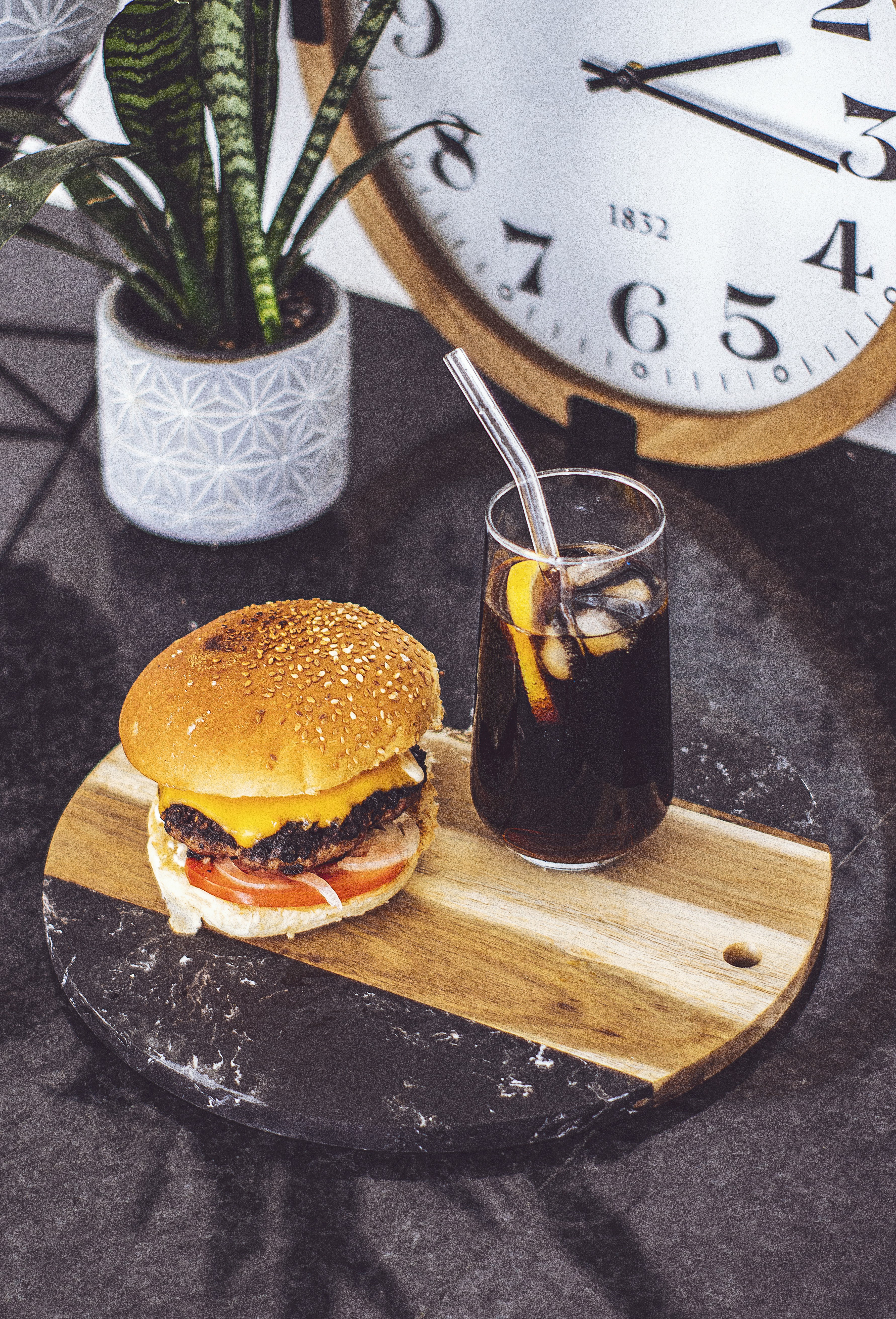 a burger and a glass of beer on a wooden cutting board