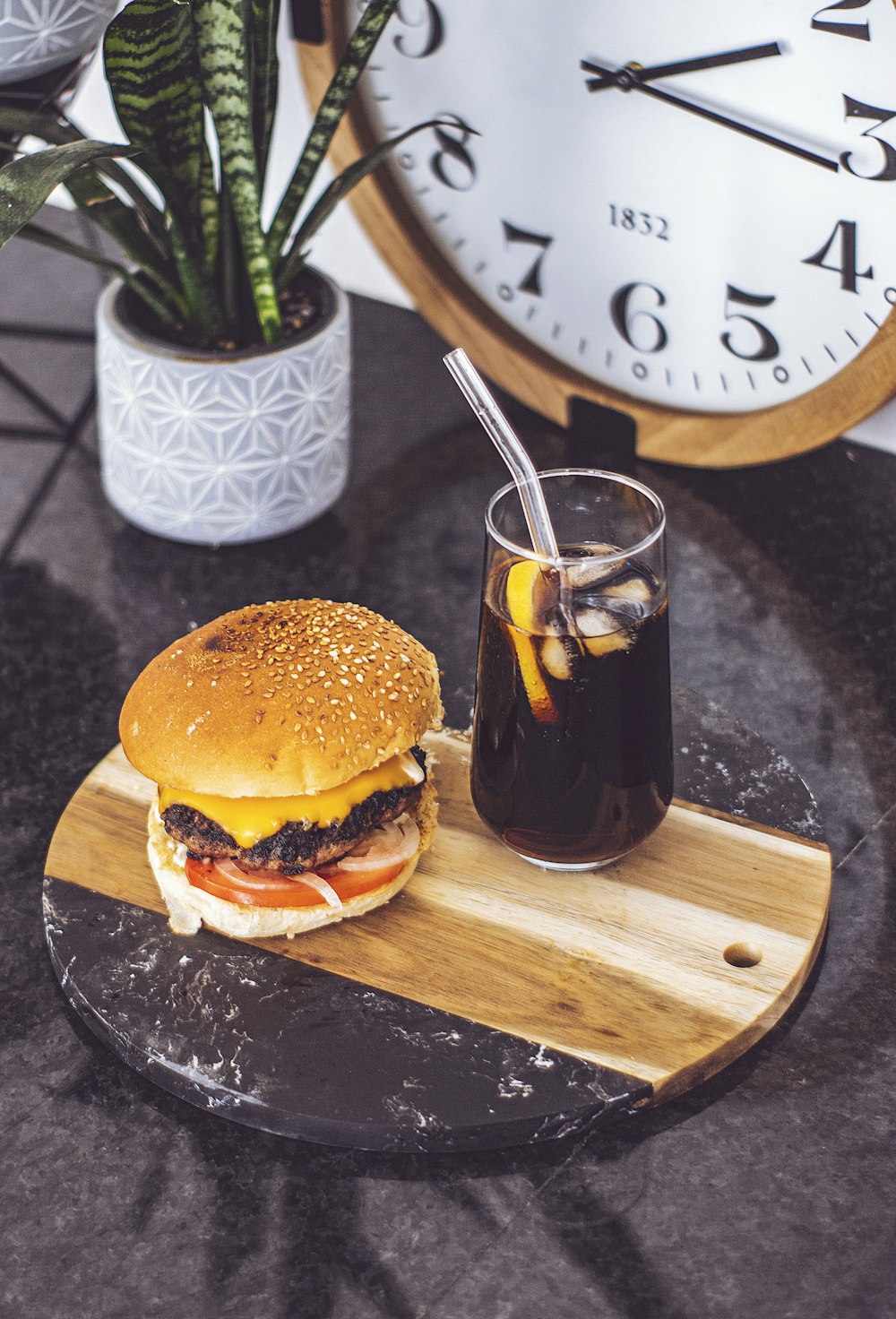 a burger and a glass of beer on a wooden cutting board