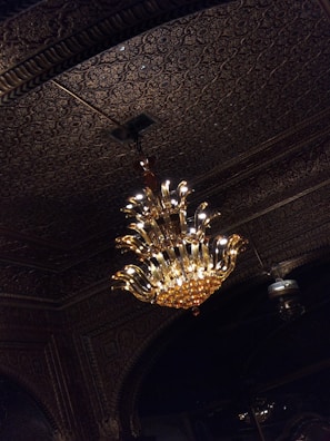A brass chandelier with intricate designs, glowing softly in a cozy living room.