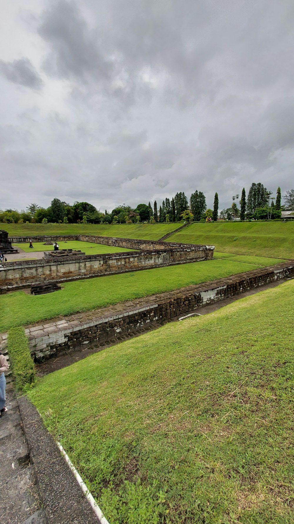 a large green field with a stone wall and a stone wall