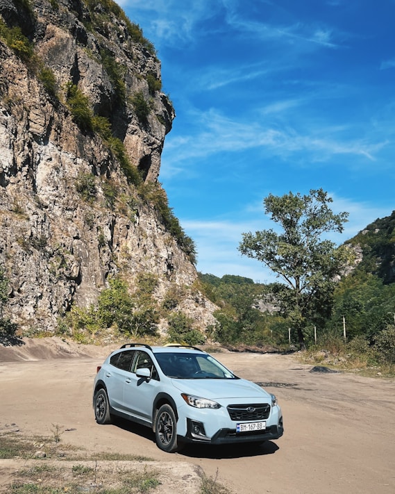 A scenic road with a ART EMPIRE rental car parked by the roadside under a clear blue sky.