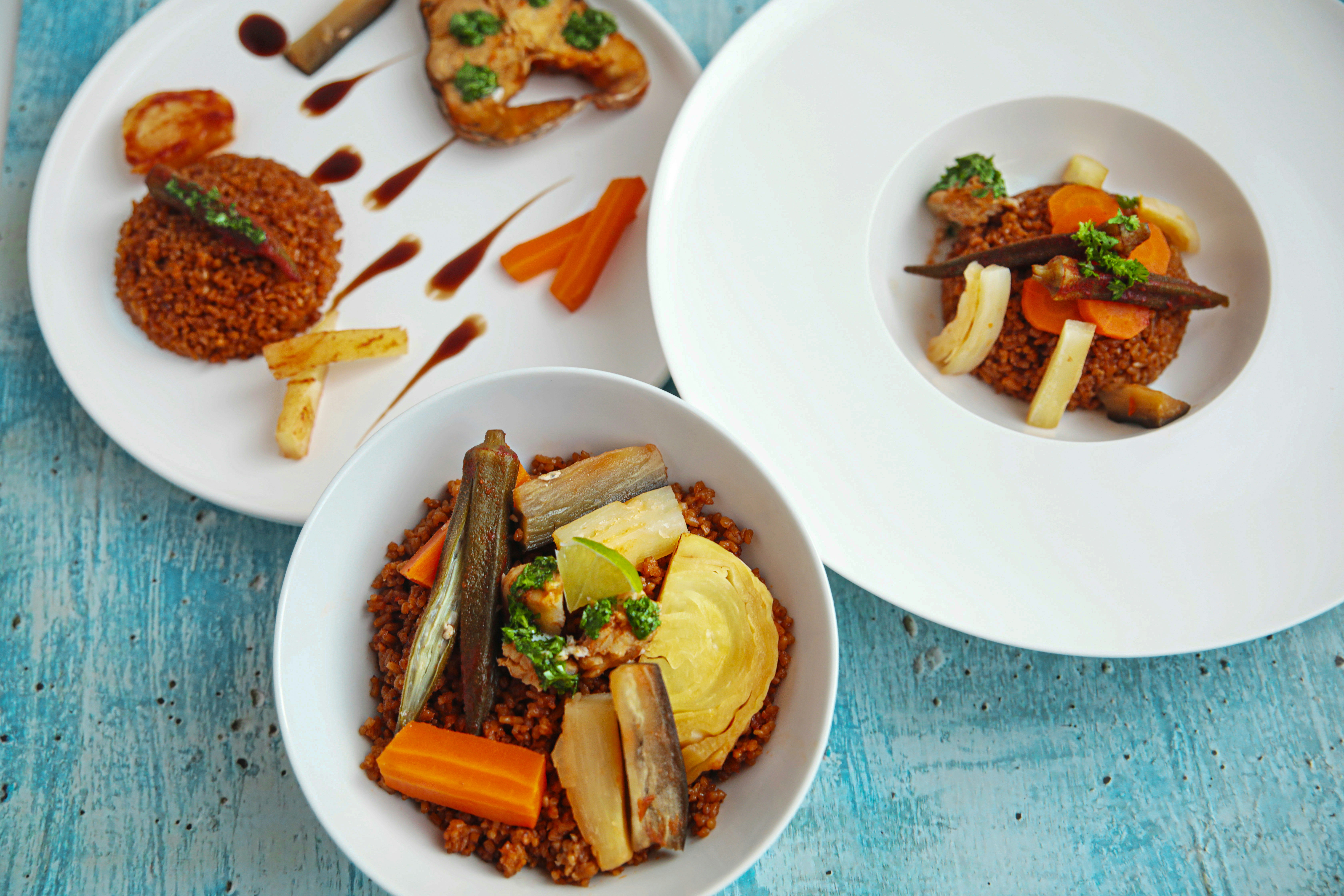 a group of plates with food on it, Elegant African Food Senegal Thieboudiènne Rouge