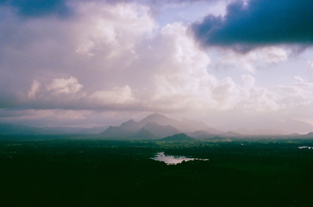 a landscape with a body of water and mountains in the background