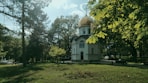 a white building with a dome and a gold roof surrounded by trees