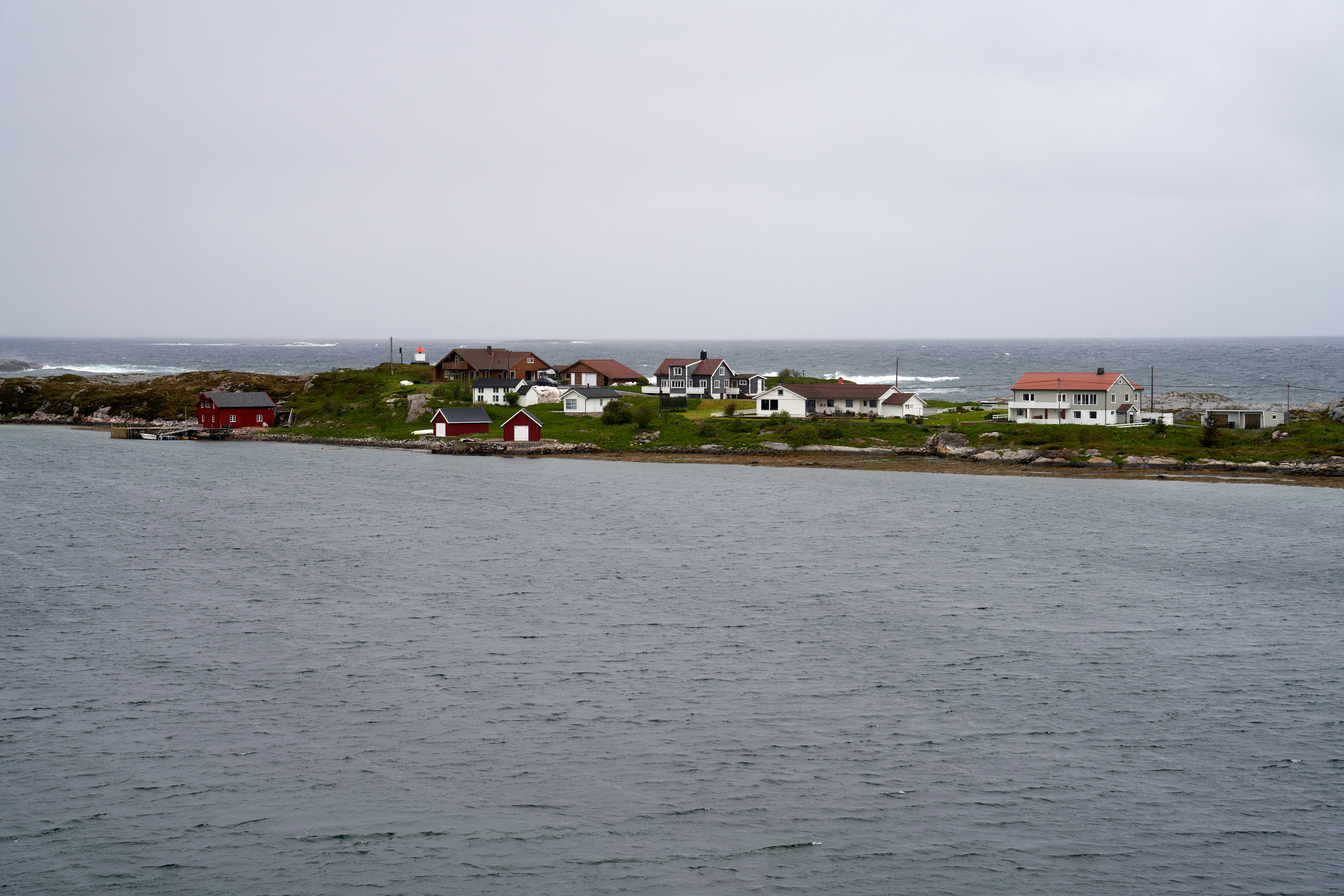 a group of houses on a hill by the water, 