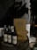 Wine bottles are placed on a wooden barrel next to stacked pizza boxes with the label 'Pizza Locale.' The setting includes a dimly lit ambiance with a potted plant nearby and a tiled wall in the background.