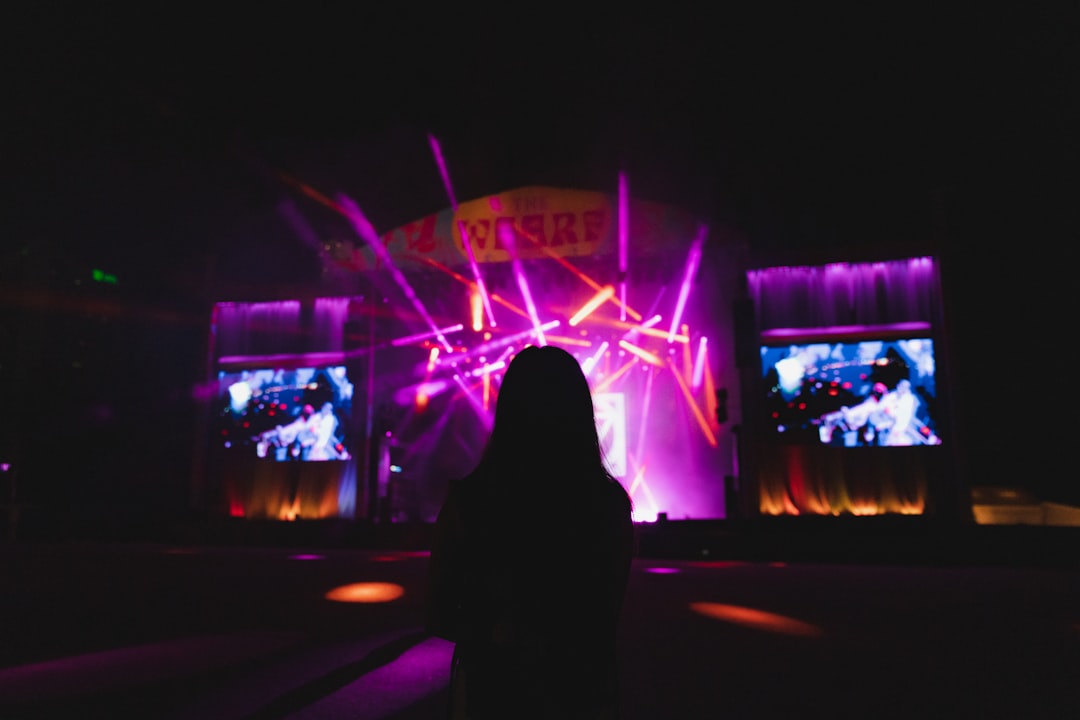 a person on a stage with a microphone in front of a large screen,