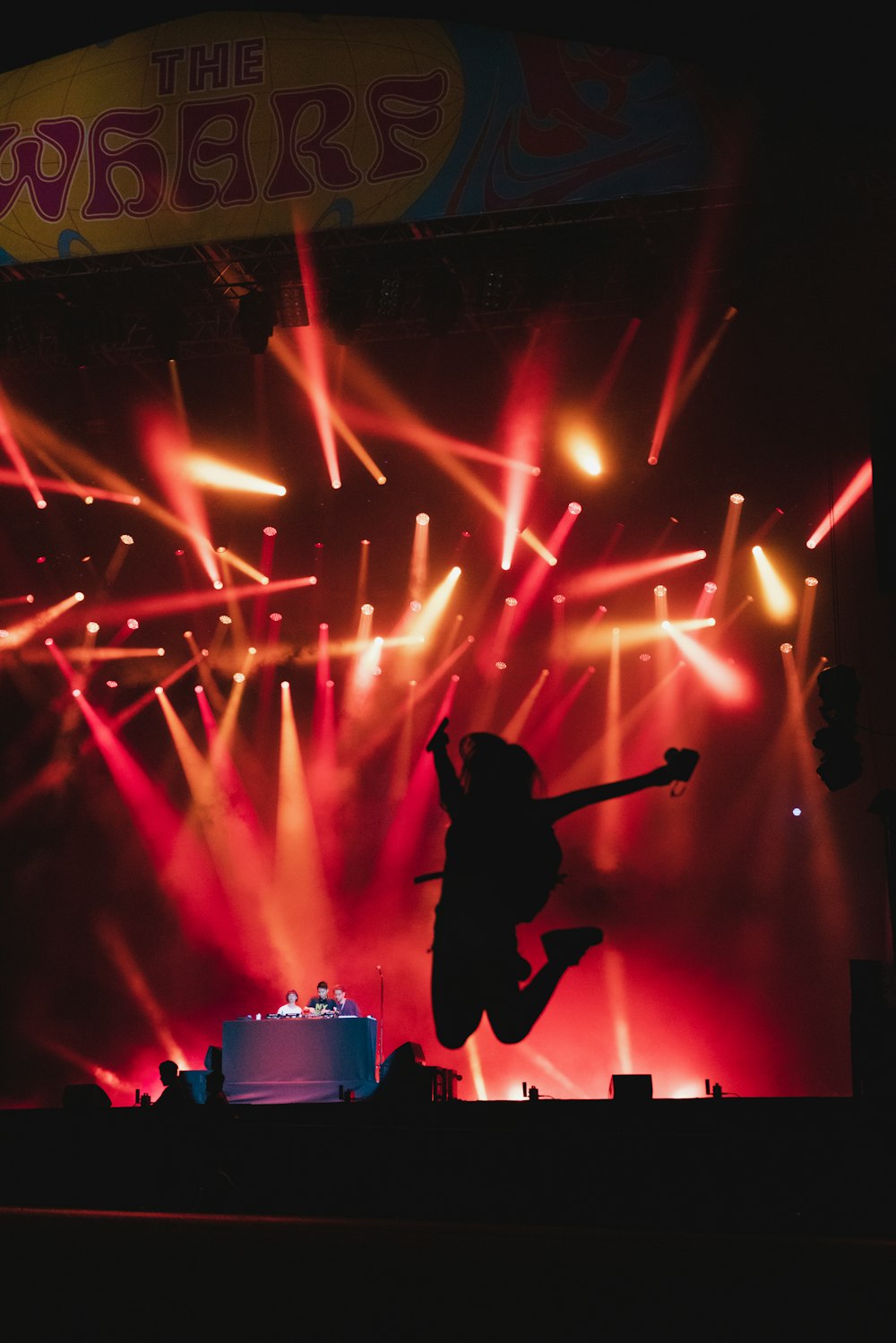 a person jumping in the air with a microphone in front of a stage