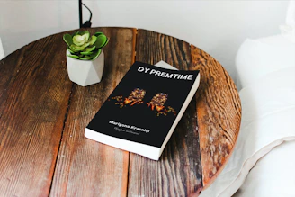 Close-up of a minimalist wooden coffee table with a small plant and a book on top.