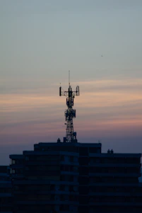 Technicians installing fiber optic cables on a telecommunications tower at sunset.