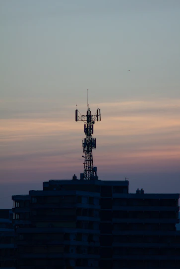 Technicians installing fiber optic cables on a telecommunications tower at sunset.