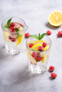 a couple of glasses with fruit and a lemon slice in them
