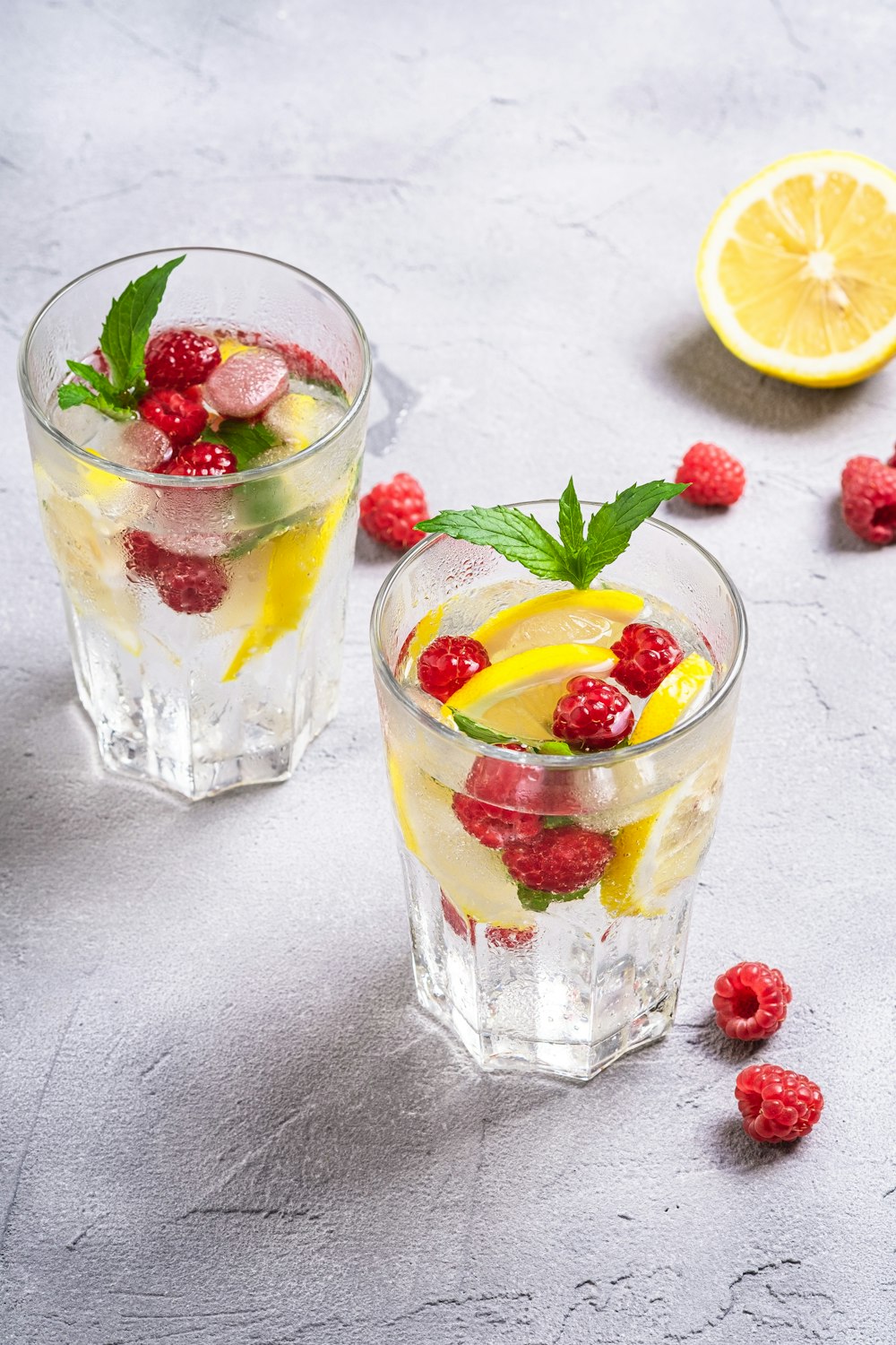 a couple of glasses with fruit and a lemon slice in them