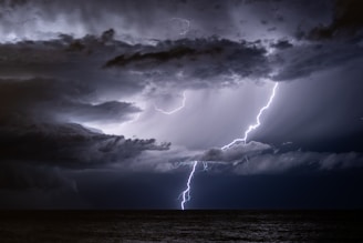 A dramatic lightning strike illuminating a stormy ocean horizon at dusk