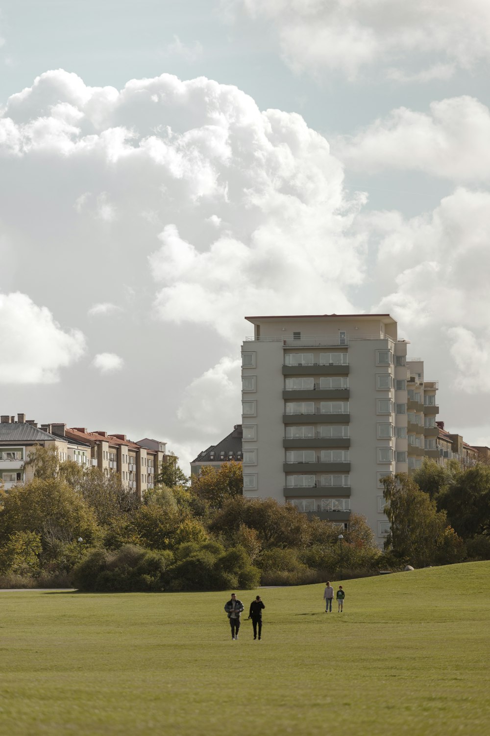 a group of people walking on a grass field in front of a building