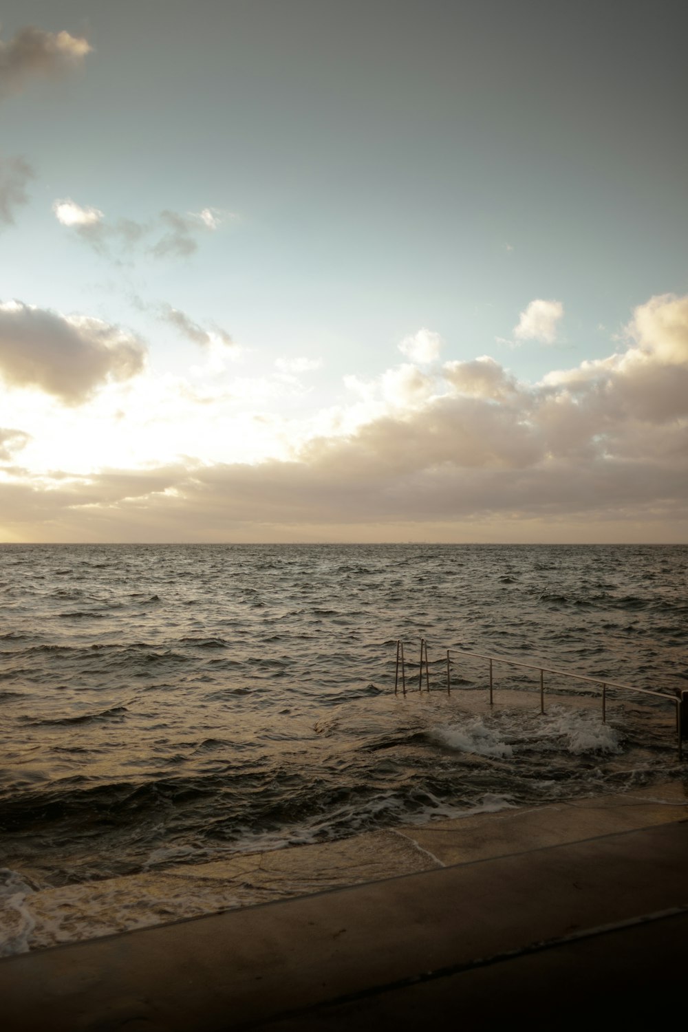 a beach with waves and a fence