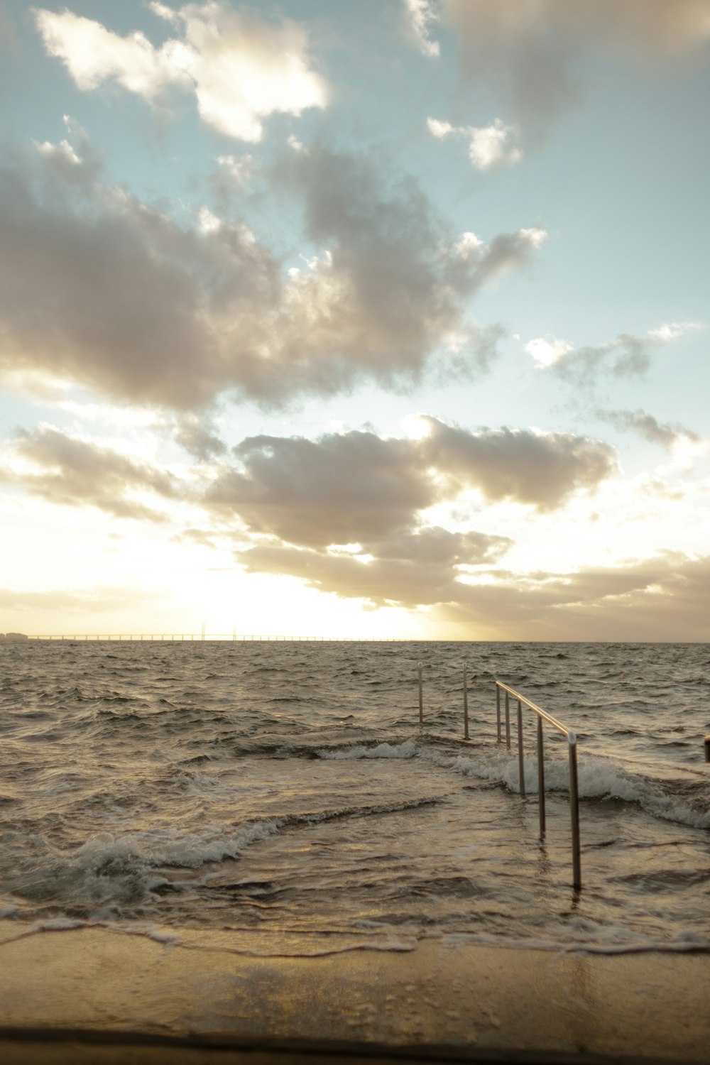 a beach with a fence and clouds