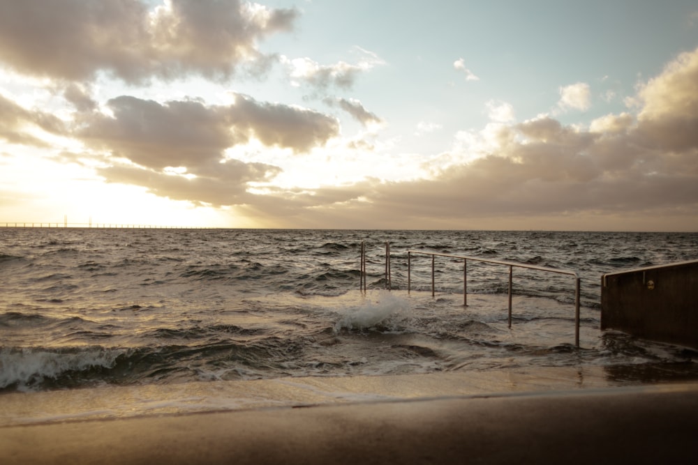 a beach with waves crashing against a wooden fence