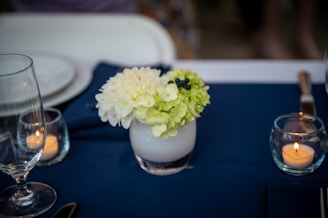 Close-up of delicate wedding table centerpiece with candles and flowers.