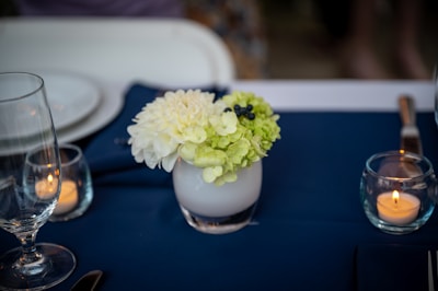 Close-up of delicate wedding table centerpiece with candles and flowers.