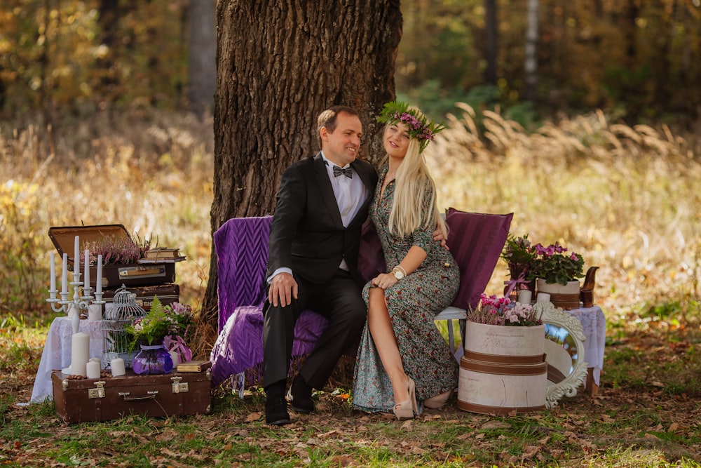 a man and woman sitting on a chair in front of a tree