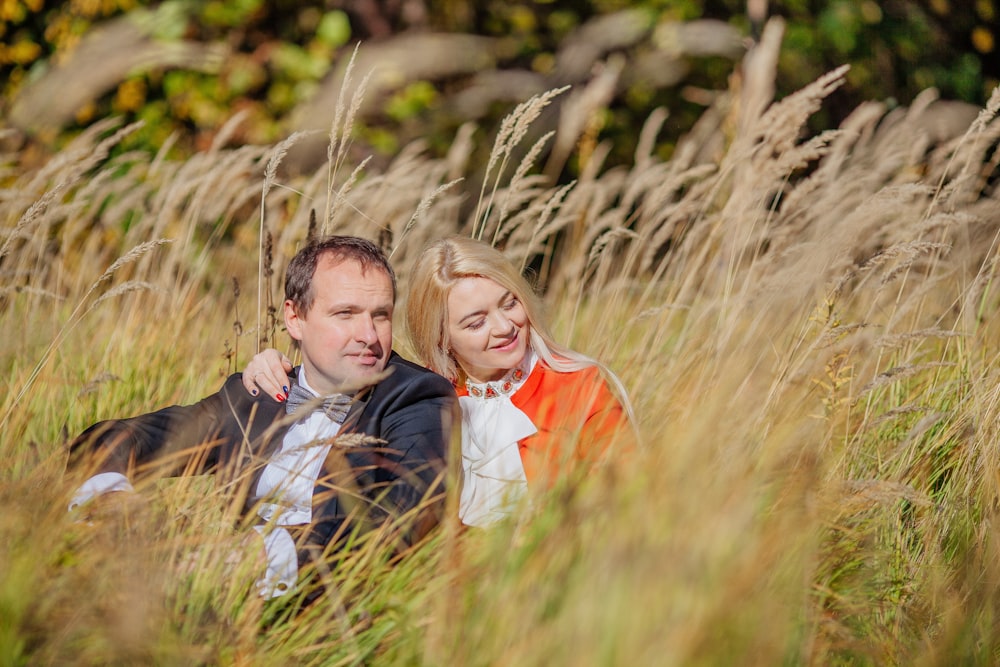 a man and woman sitting in tall grass