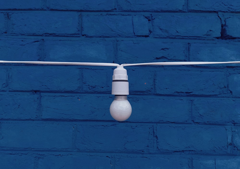 a white light bulb on a blue wall