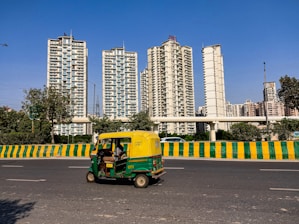 A vibrant auto rickshaw navigating through a busy city street during the day.