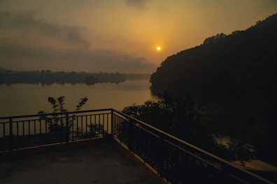 Private balcony overlooking a calm lake at sunset with comfortable seating.