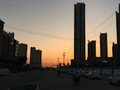 Cityscape with electric vehicles and renewable energy infrastructure at sunset.