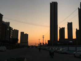 Cityscape with electric vehicles and renewable energy infrastructure at sunset.