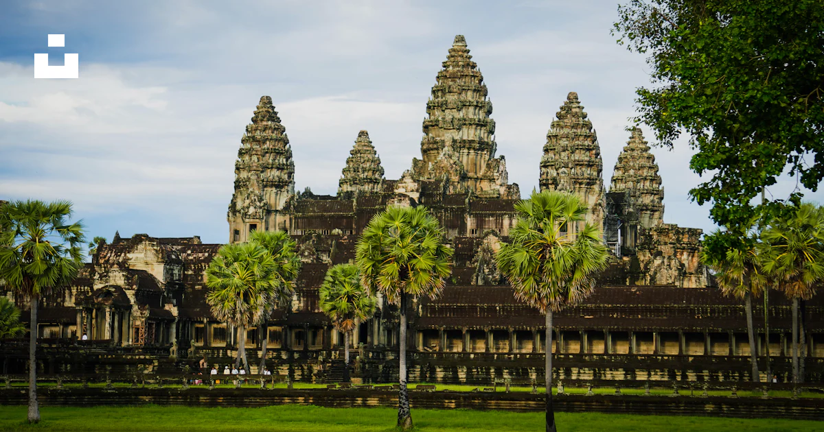 Wat Religious Building A large building with towers and palm trees with Angkor Wat in the ...