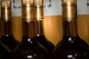 Sleek, dark bottles of St Daniel lined up on a polished black marble surface with gold accents reflecting softly.