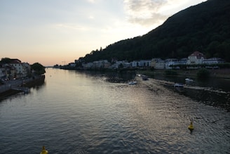 A serene riverside view of Kampot at sunset with traditional boats floating gently.