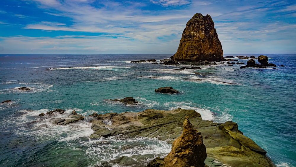 a rocky beach with a large body of water in the background with Roques de Anaga in the background