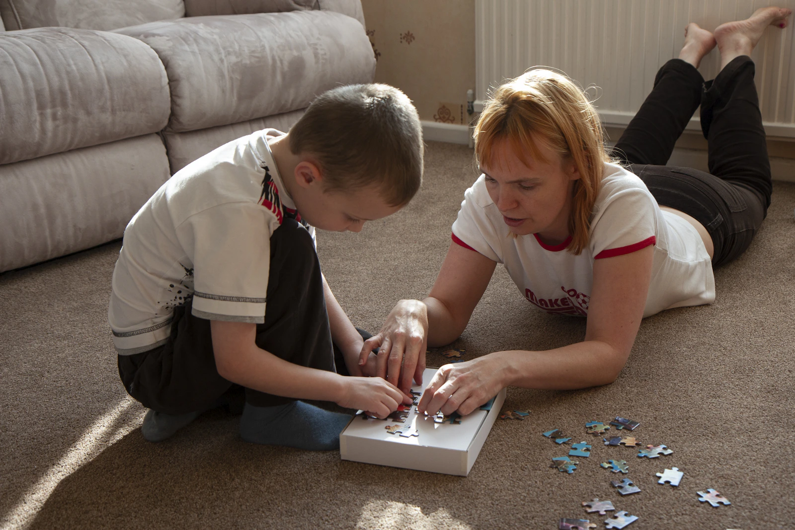 Parent and child solving a colorful jigsaw puzzle together at home