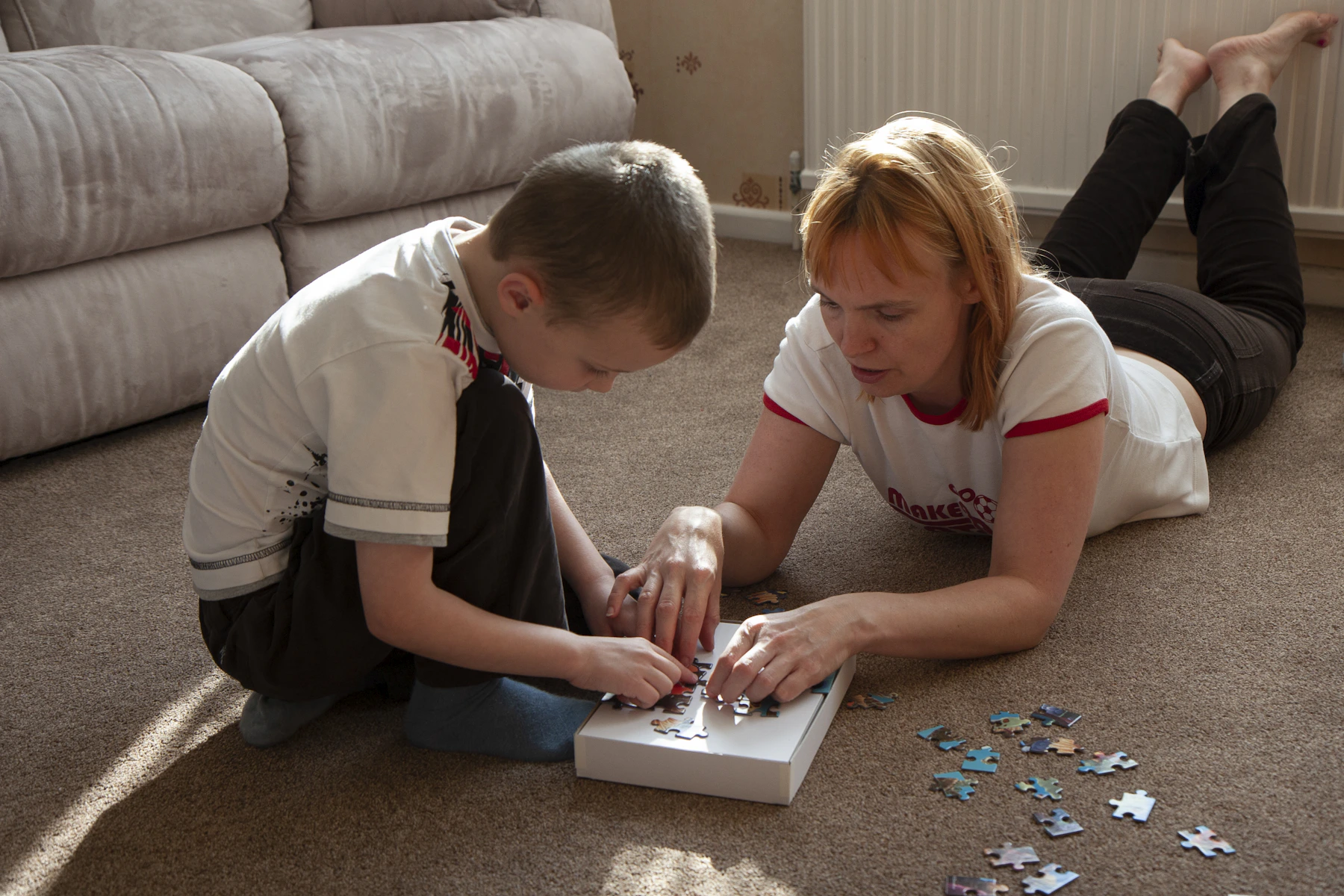 Parent and child working together on a colorful jigsaw puzzle at home