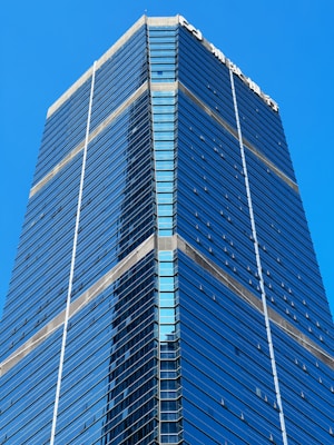 A tall, modern skyscraper with a sleek design featuring glass and steel elements. The building