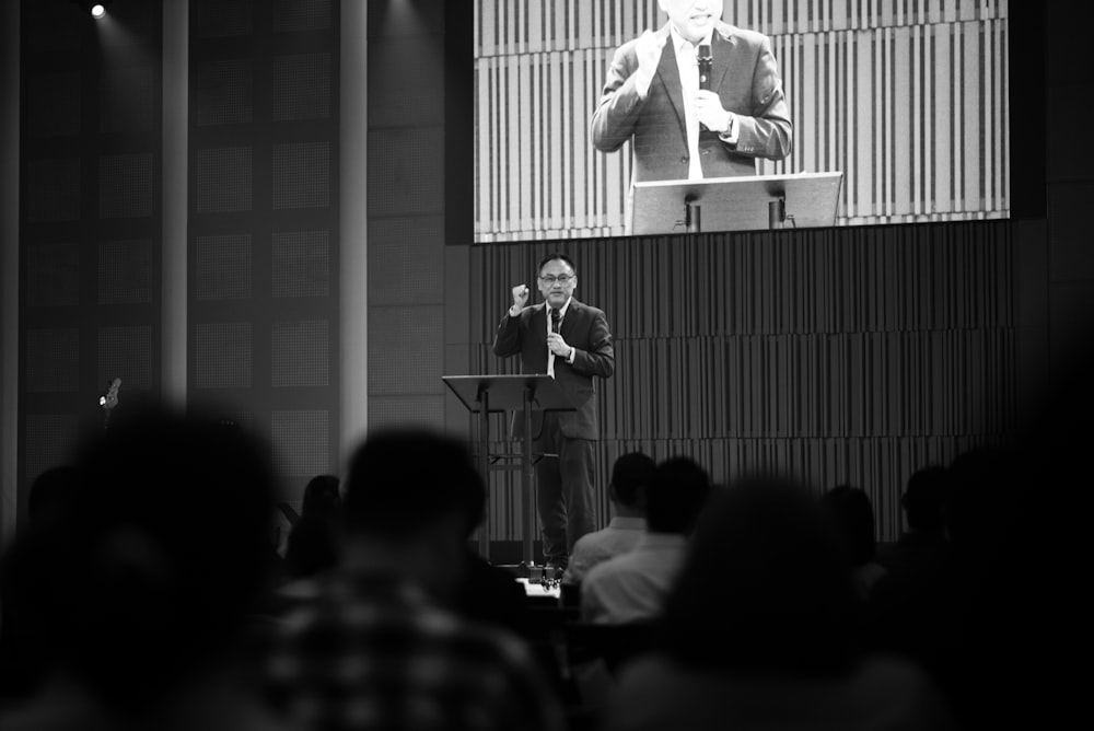 a person speaking into a microphone in front of a crowd