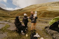a group of people sitting on a hill with a tent and a mountain in the background