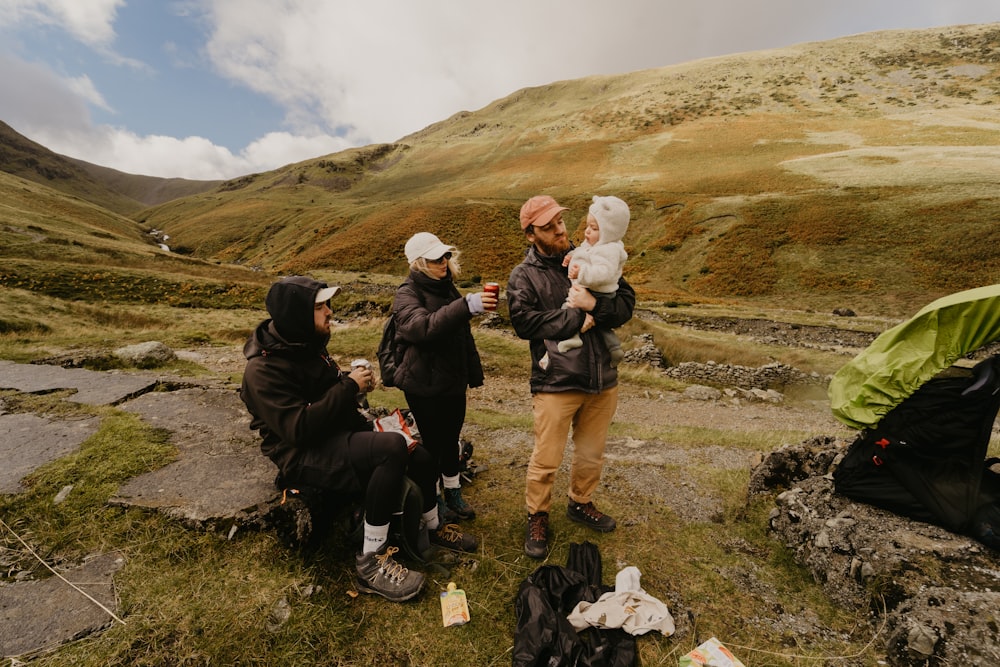 a group of people sitting on a hill with a tent and a mountain in the background