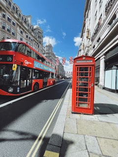 A vibrant street scene in London featuring iconic double-decker buses and red phone booths.