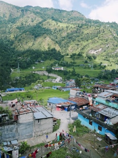 a group of buildings and trees with a hill in the background